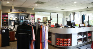 Interior of a golf shop featuring clothing racks, golf equipment, and a checkout counter.