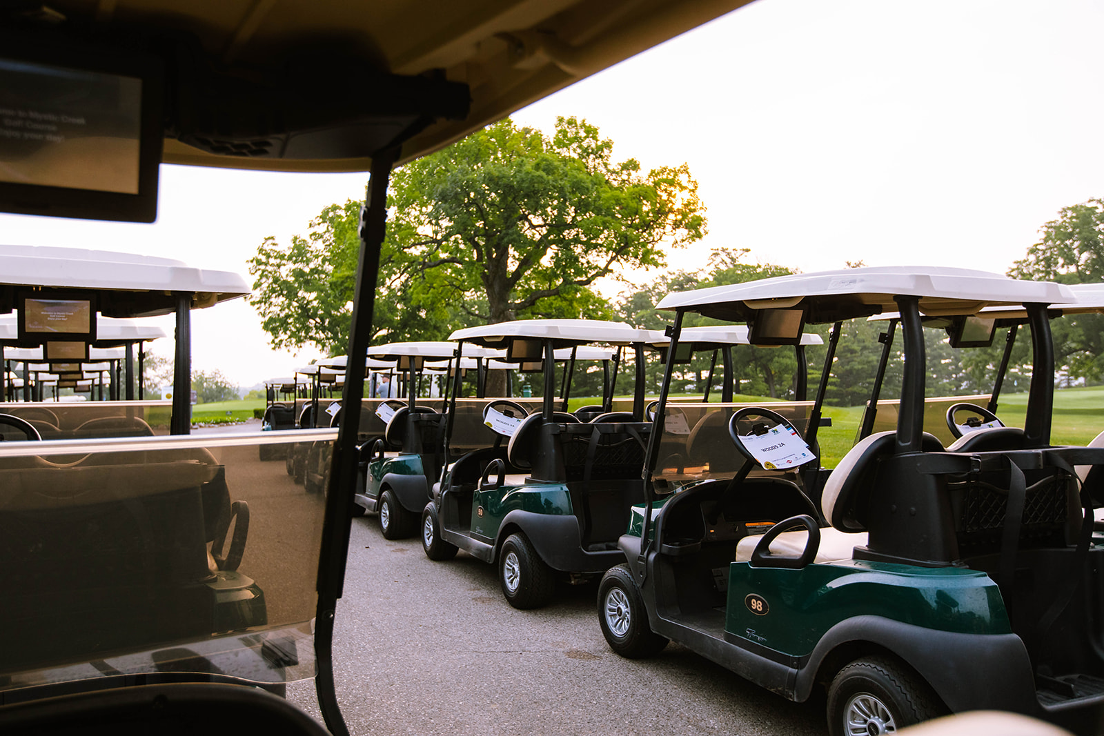 Row of golf carts parked on a path with trees in the background at Camp Dearborn.